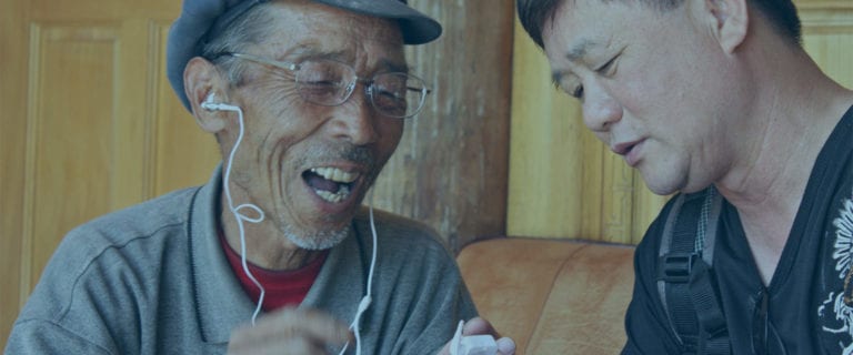 An elderly man listens to the Bible.is app through headphones in his native language for the first time.