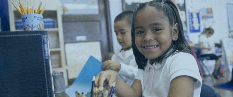 A young girl happily works in a classroom