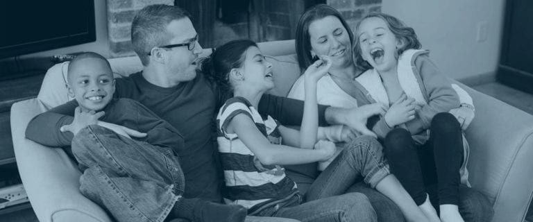 A family laughing with each other sitting on a couch