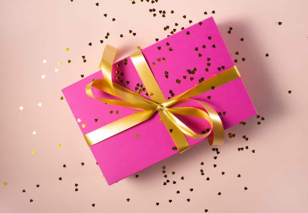 A pink gift box tied with gold ribbon