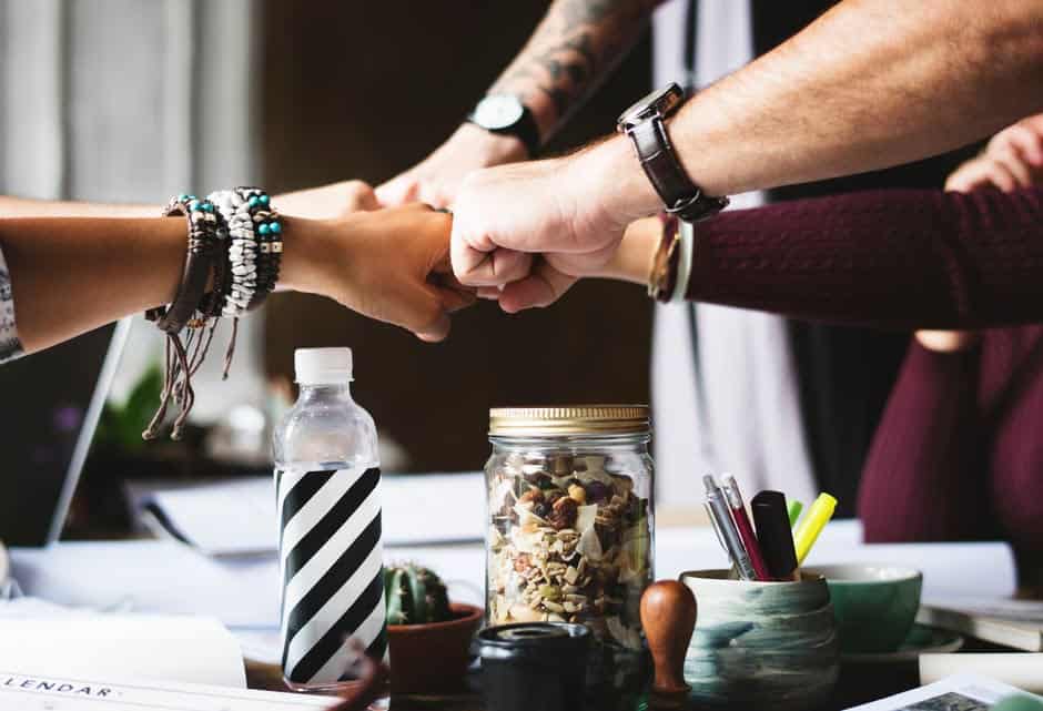 A closeup shot of a team of coworkers fist bumping.