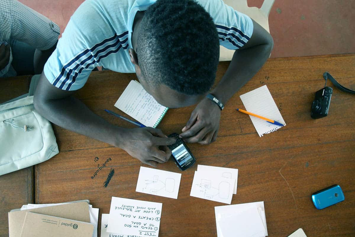 A young man uses a cell phone to test a prototype for a CauseLabs project.