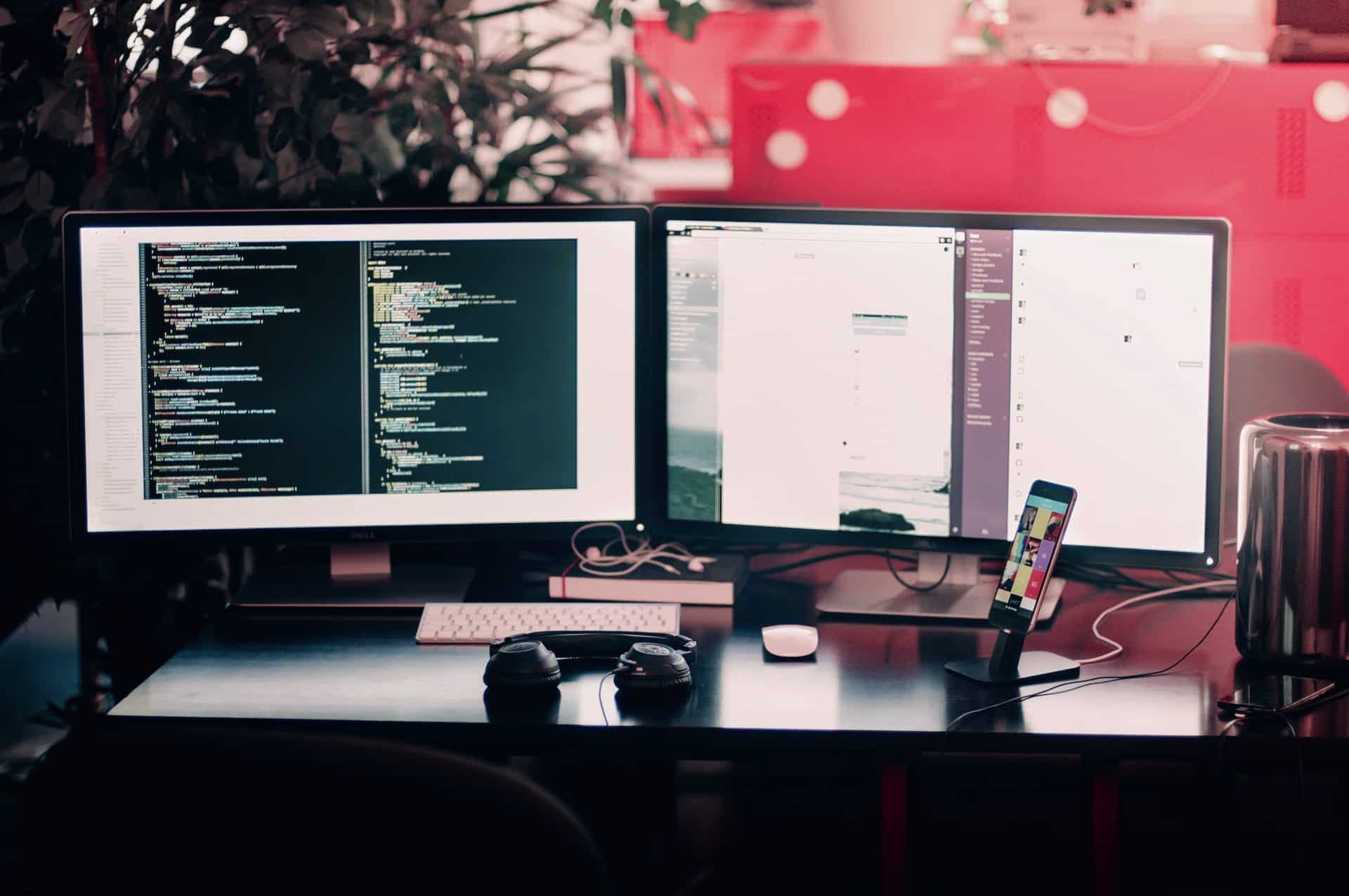 A desk with two monitors displaying code.