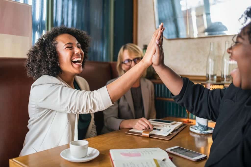 Two women high-five at a table.