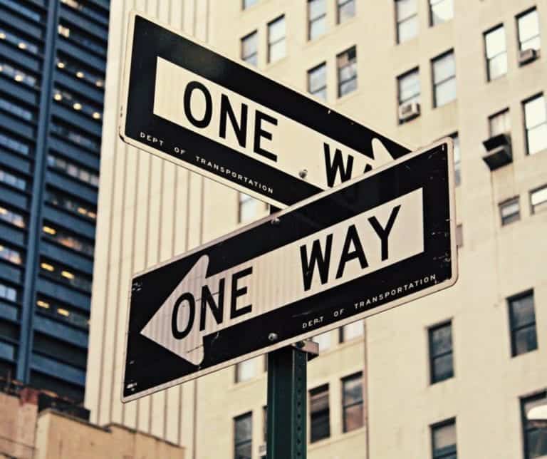A pole with two one-way signs attached point different directions.