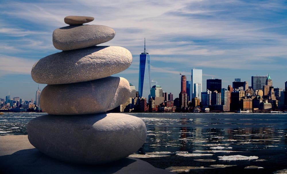 Stacked stones by the water with a city skyline