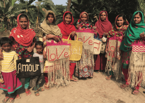 A group of village women hold hand-made bags.