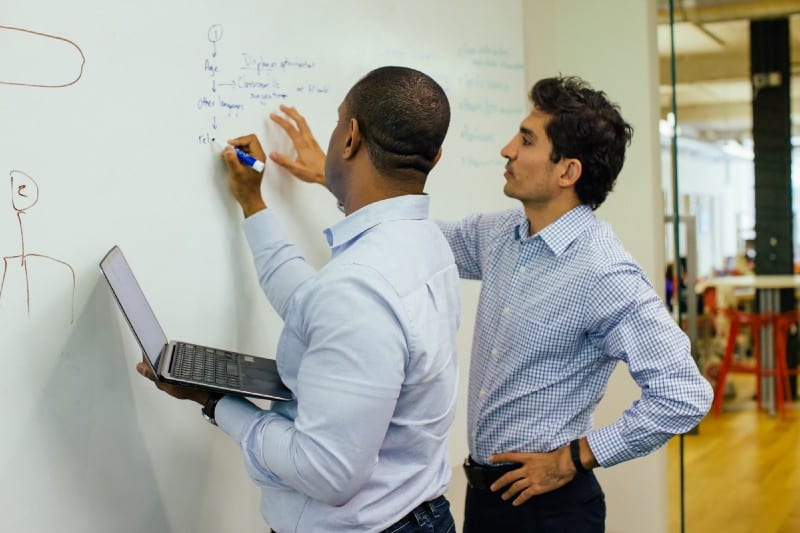 An HCD workshop for education website where two men are writing out ideas on a whiteboard