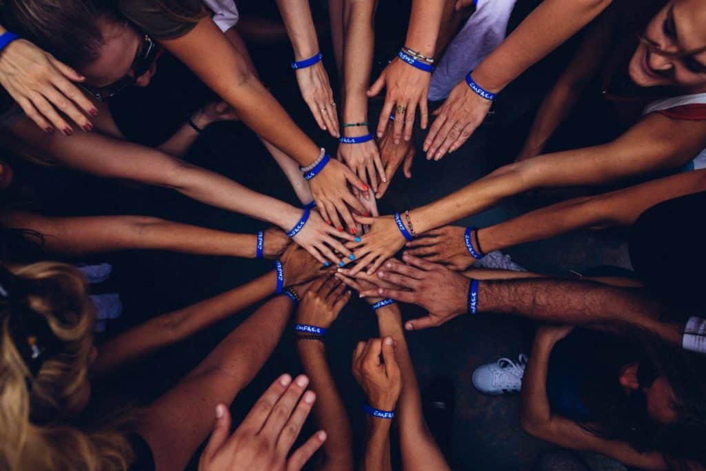 A diverse group of people in a circle with their hands in the center