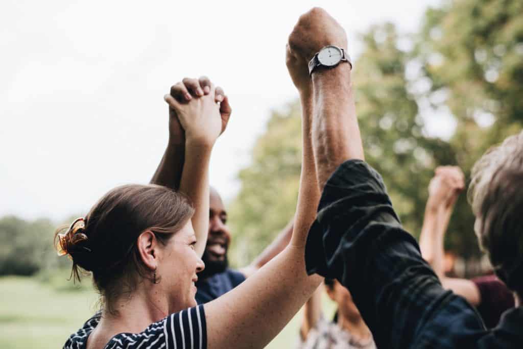 A diverse group of people holding hands in the air. A photo for our social impact post.