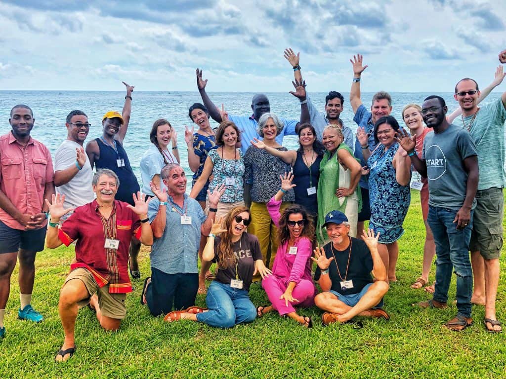 21 OC delegates pose for a fun group photo on a grassy hill by the ocean.