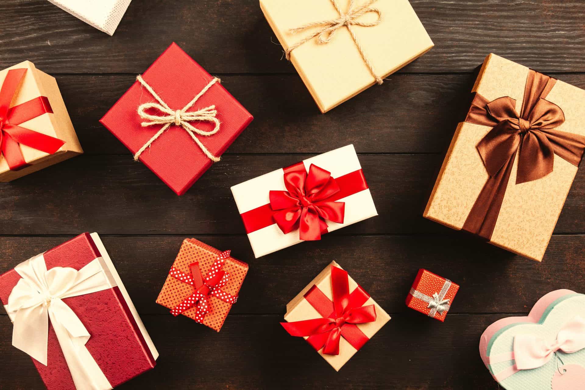 Red and gold holiday gift boxes, scattered on a brown wooden surface