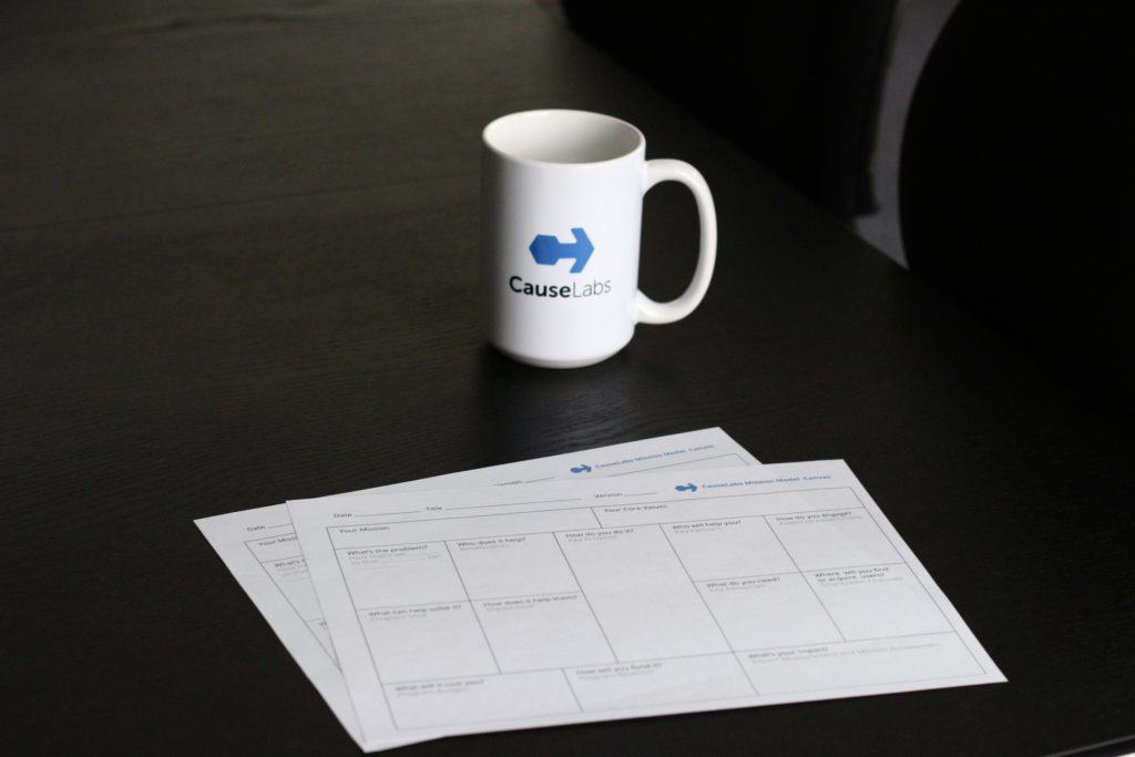 The Mission Model Canvas on a black table with a CauseLabs mug.