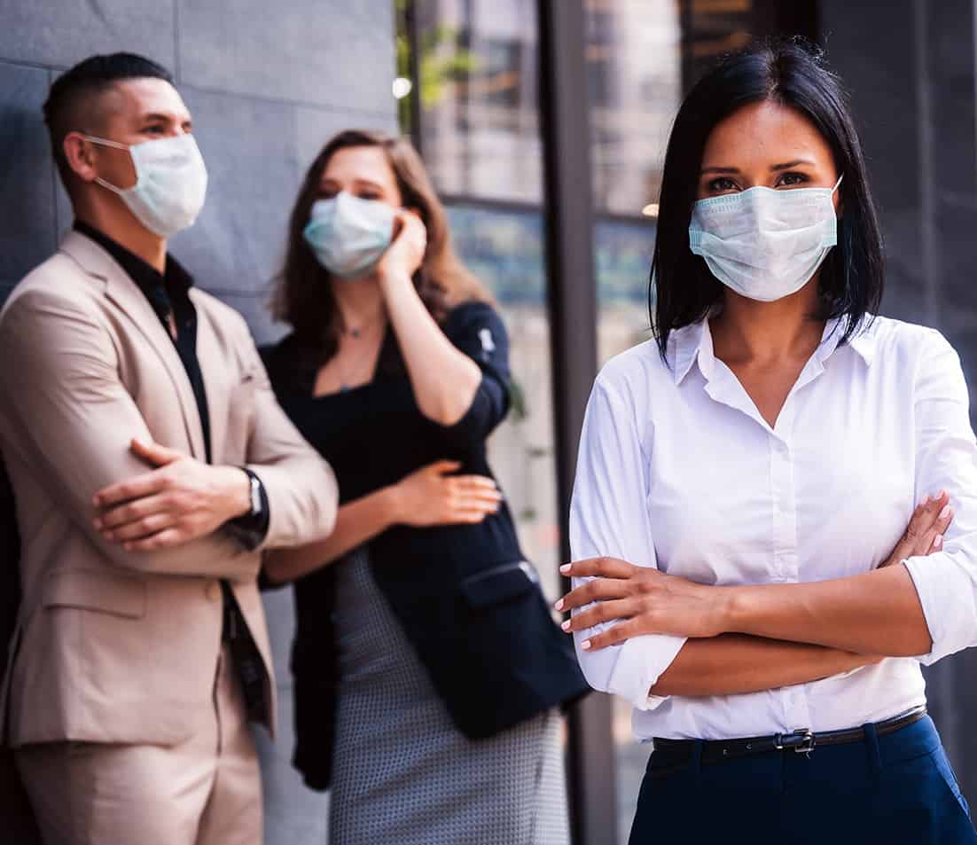 Business workers having a conversation and woman looking at the camera with masks on.