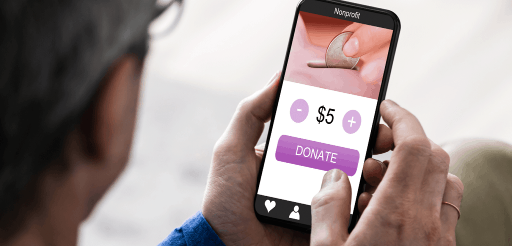 A man holds a cell phone that is displaying a donate button for a non profit