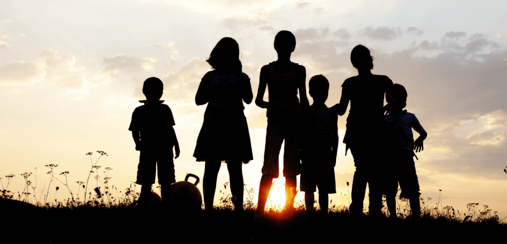 A group of children on a hill, they are in shadow and the sun is behind them