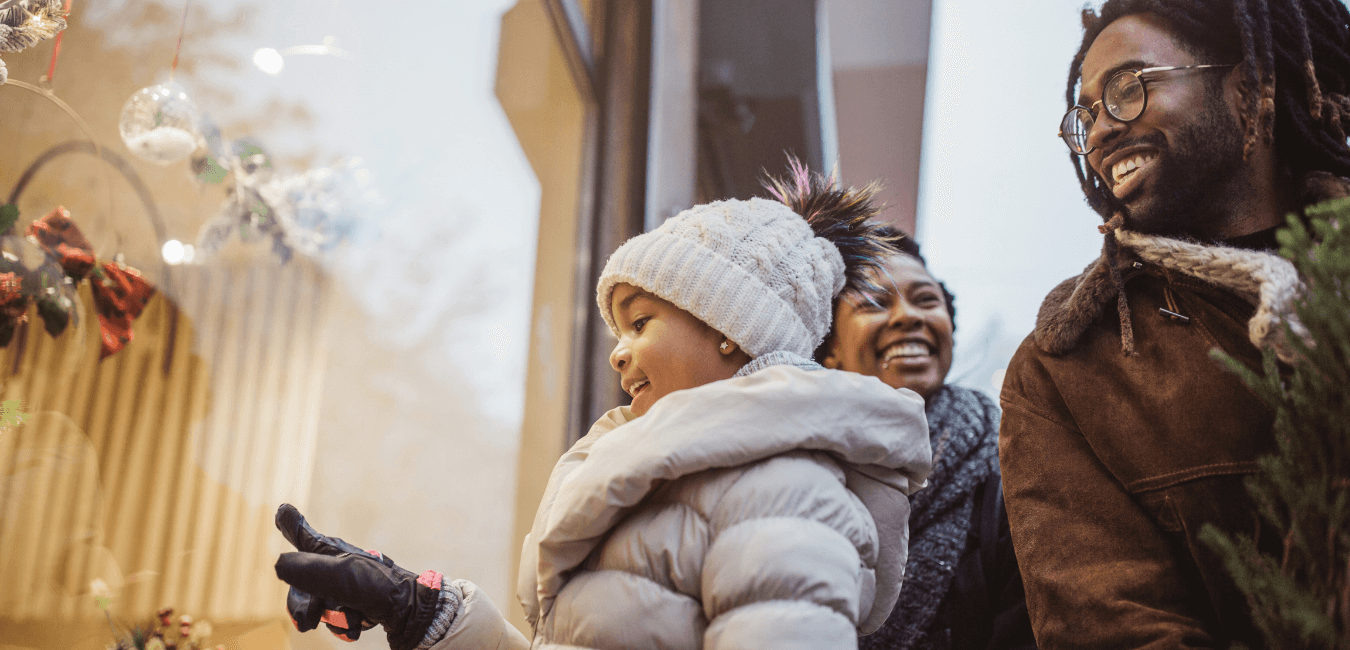 Girl looking out of the window with her parents for holiday shopping looking what to buy