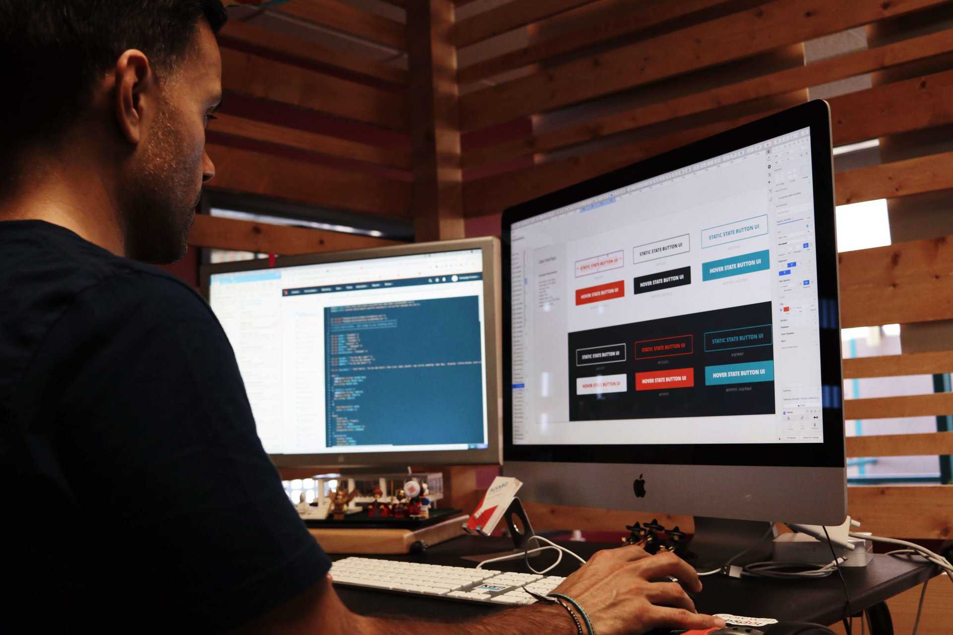 A man designing a website on two computer monitors.