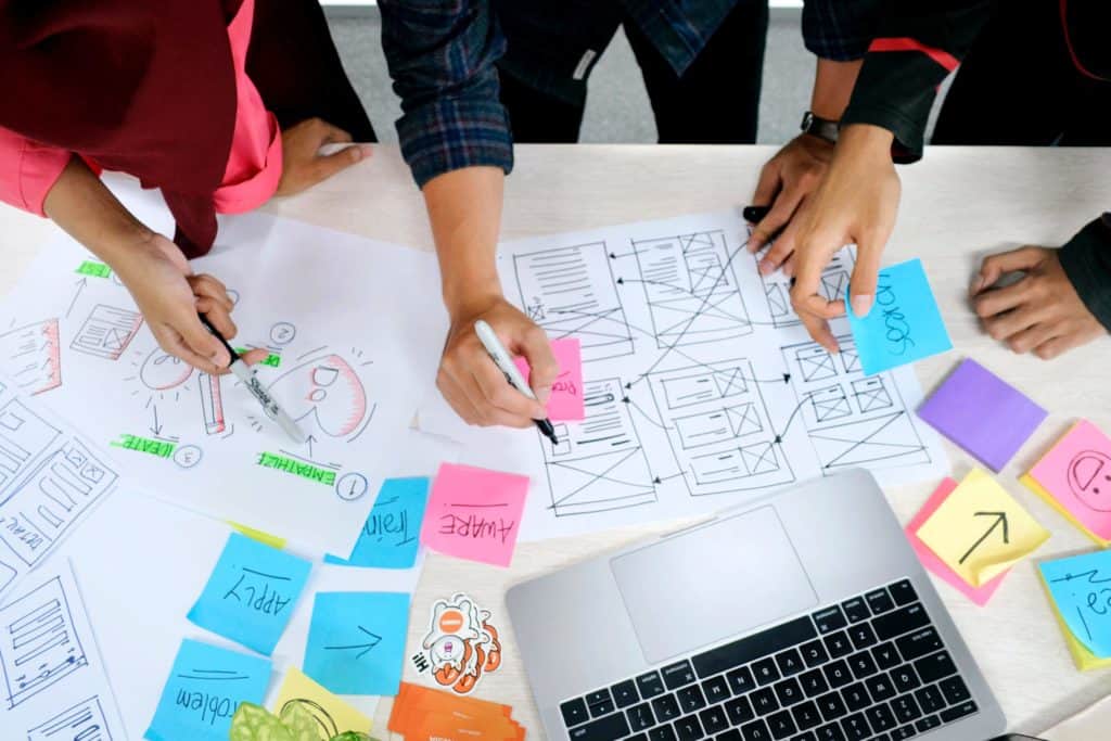 Continuous Improvement in Growth-Driven Design: A close up of three people's hands as they plan out website content.