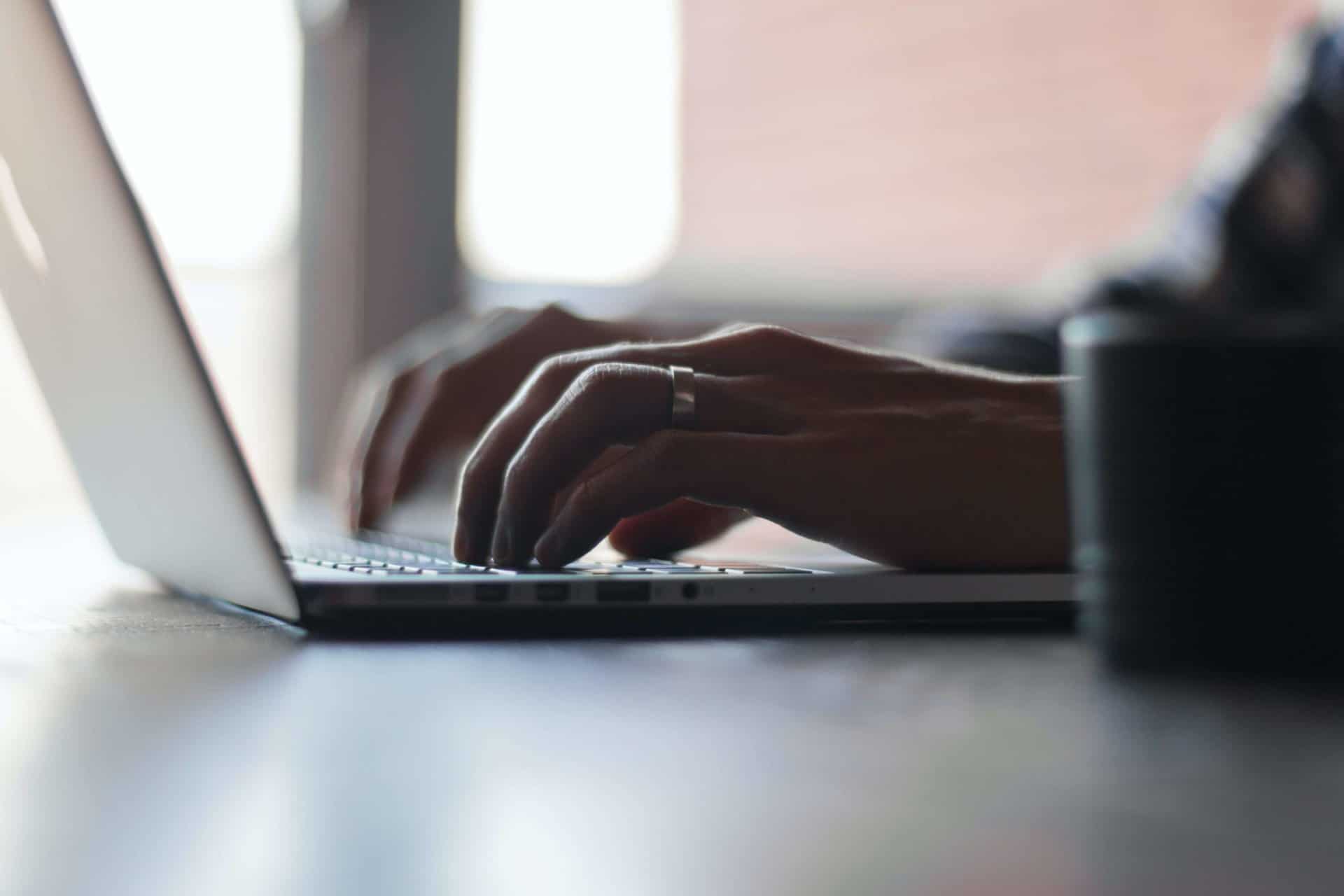 Hands typing on a laptop