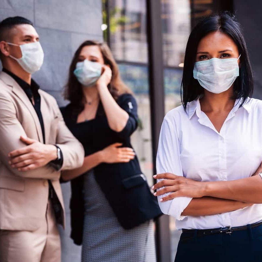 Business workers having a conversation and woman looking at the camera with masks on.