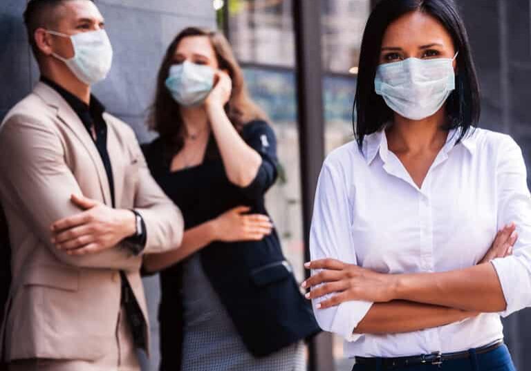 Business workers having a conversation and woman looking at the camera with masks on.
