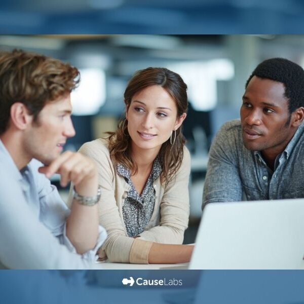 CauseLabs-Team-Working-on-a-Website Three people sit at a table in an office, engaged in conversation, with a laptop open in front of them. The CauseLabs logo appears at the bottom of the image.
