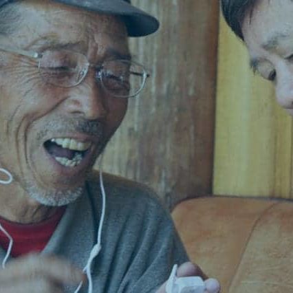 An elderly man listens to the Bible.is app through headphones in his native language for the first time.