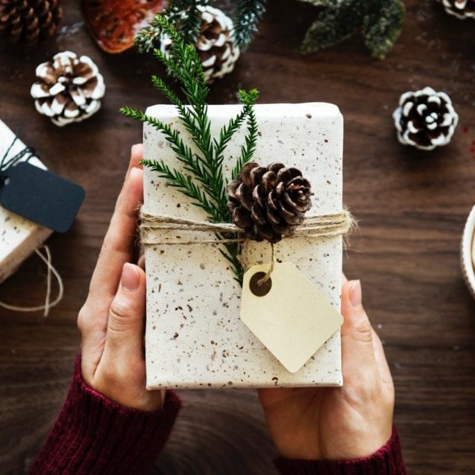 Gift A close up image of two hands holding a rustically wrapped gift.