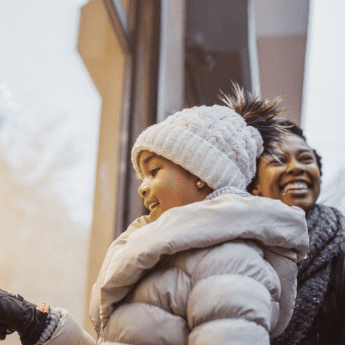 Girl looking out of the window with her parents for holiday shopping looking what to buy