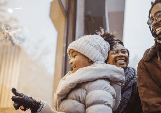 Girl looking out of the window with her parents for holiday shopping looking what to buy