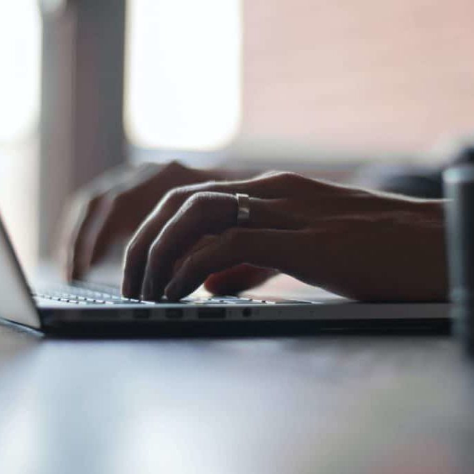 Hands typing on a laptop