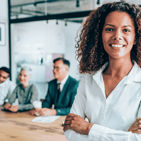 Woman of color with natural hair smiling in front of her team in office