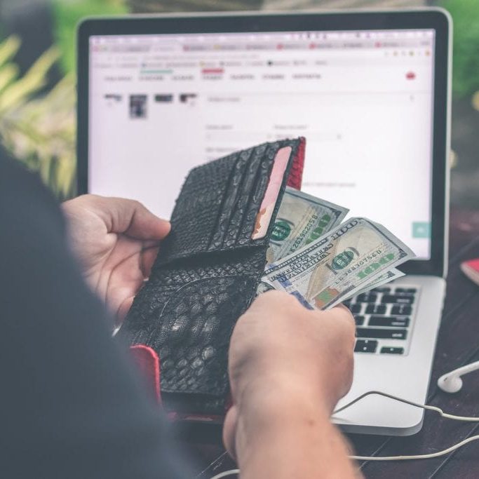 artem-bali-590545-unsplash (1) Looking over the shoulder of a person who is counting the money in their wallet.