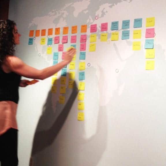 A woman places a sticky note on a wall during a CauseLabs strategic workshop