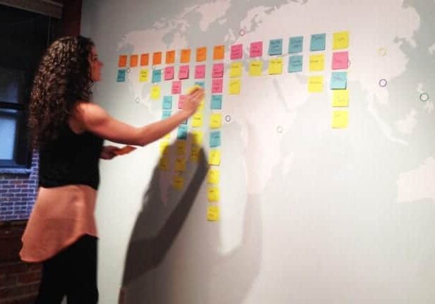 A woman places a sticky note on a wall during a CauseLabs strategic workshop