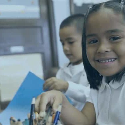 A young girl happily works in a classroom