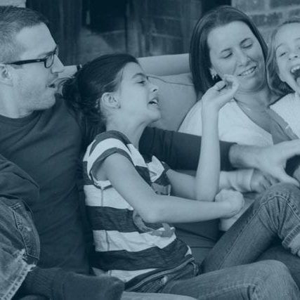 A family laughing with each other sitting on a couch