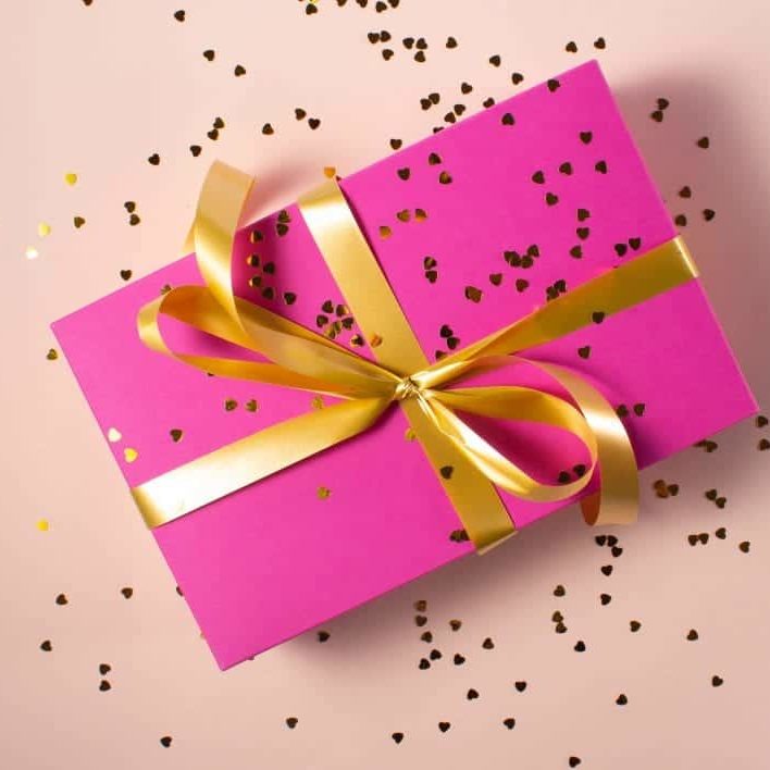 A pink gift box tied with gold ribbon