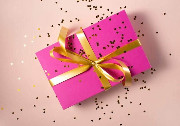 A pink gift box tied with gold ribbon