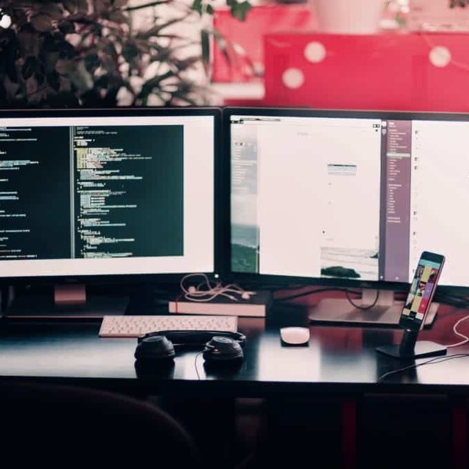 A desk with two monitors displaying code.