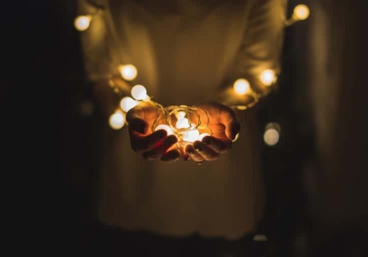 A person holds a bundle of glowing holiday lights in their hands