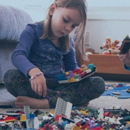 A young girl and boy play with LEGOs.