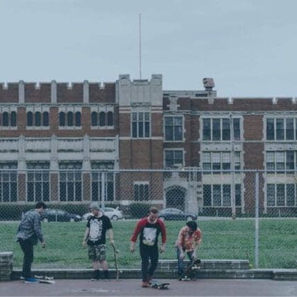 Several young people skateboard in a vacant parking lot.