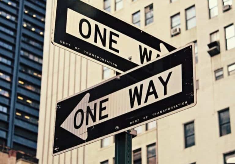 A pole with two one-way signs attached point different directions.
