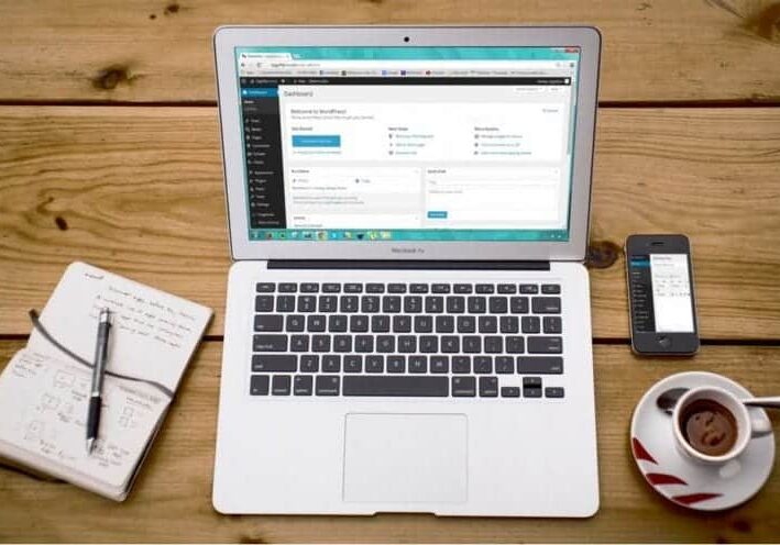 A laptop displays the WordPress admin dashboard.