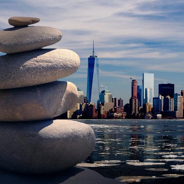 Stacked stones by the water with a city skyline