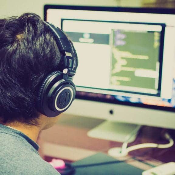 A man wearing headphones works at a computer station.