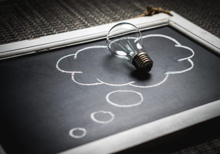 A small chalkboard with a thought bubble drawn on it and a lightbulb sitting on top of the bubble