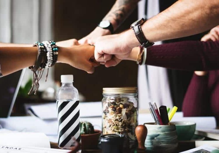 A closeup shot of a team of coworkers fist bumping.